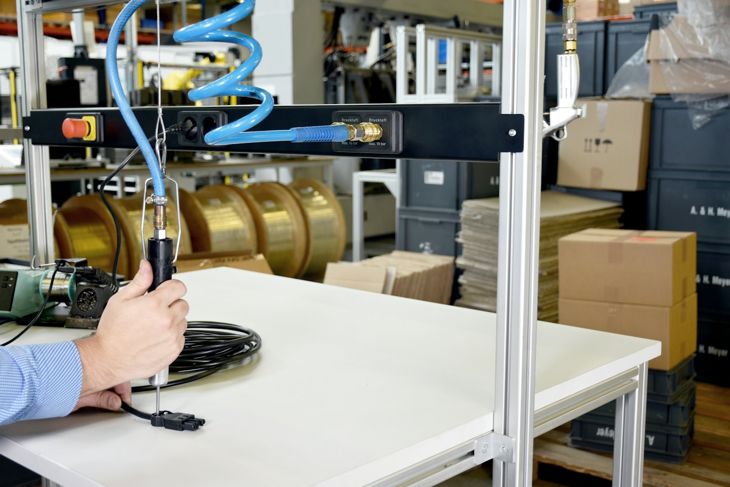 Händer använder ett pneumatiskt verktyg för att montera en elektronisk komponent.